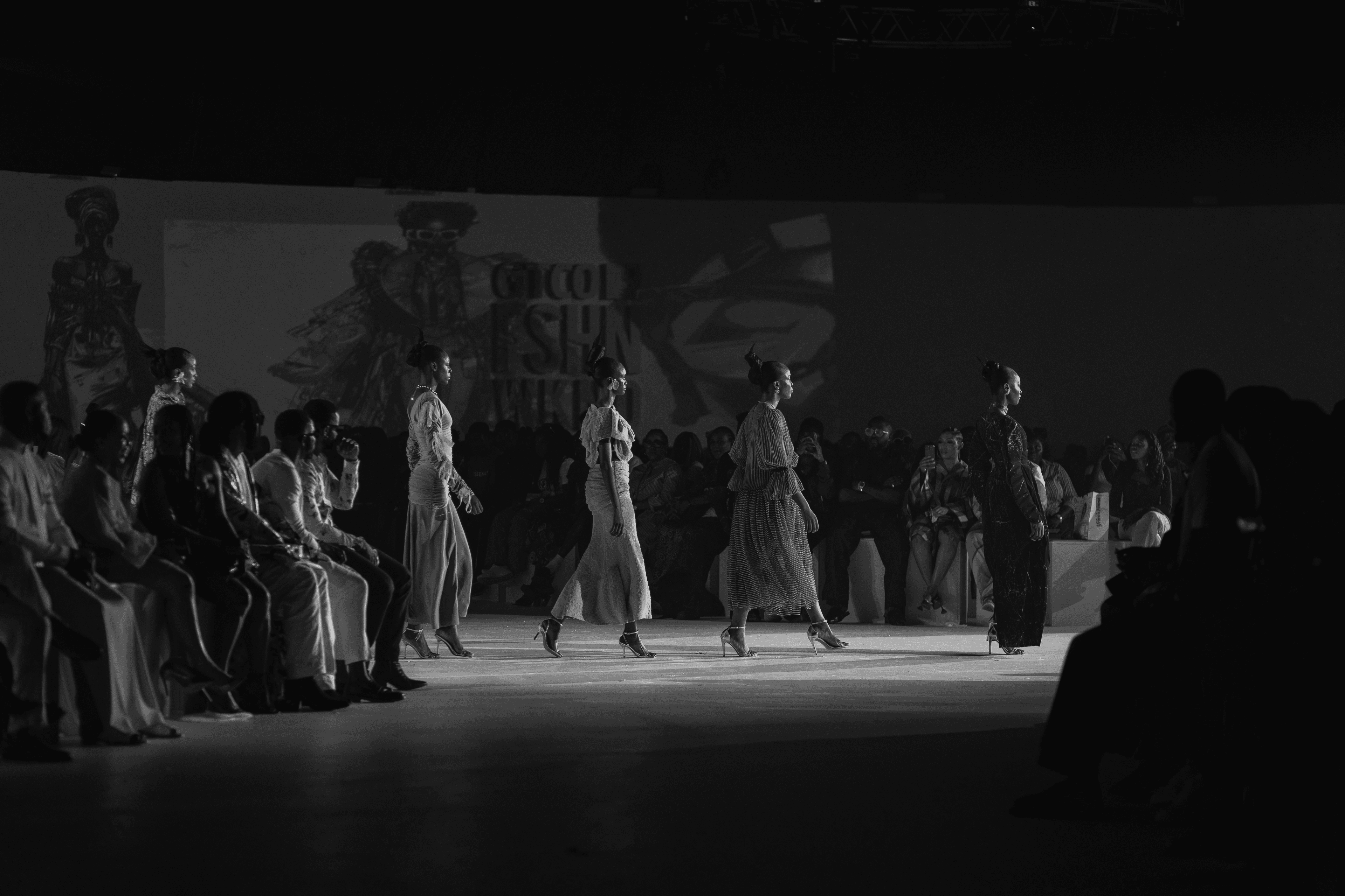 Models on the runway at a fashion showcase, in black and white