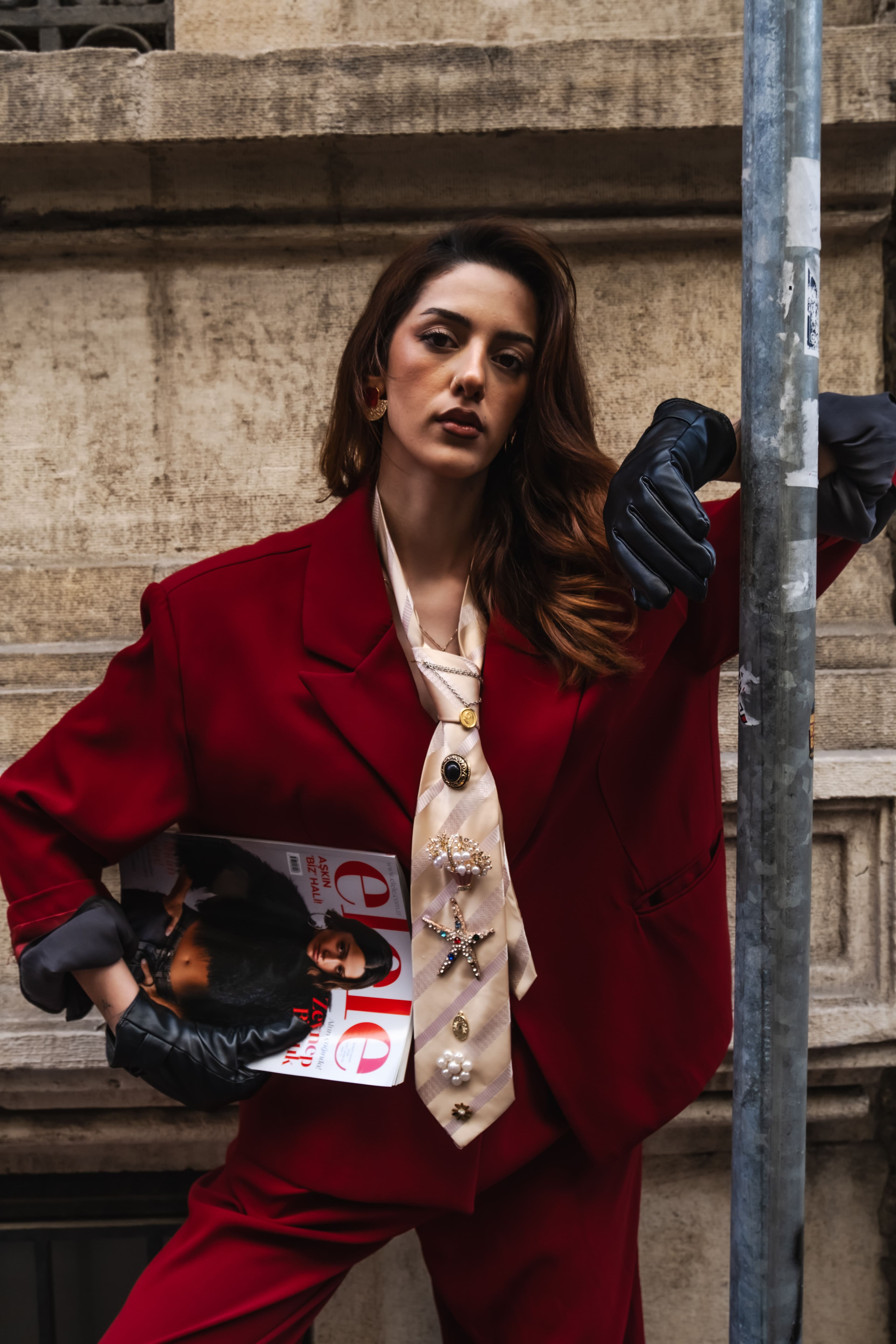 A woman in a tailored red suit and silk tie on a city street