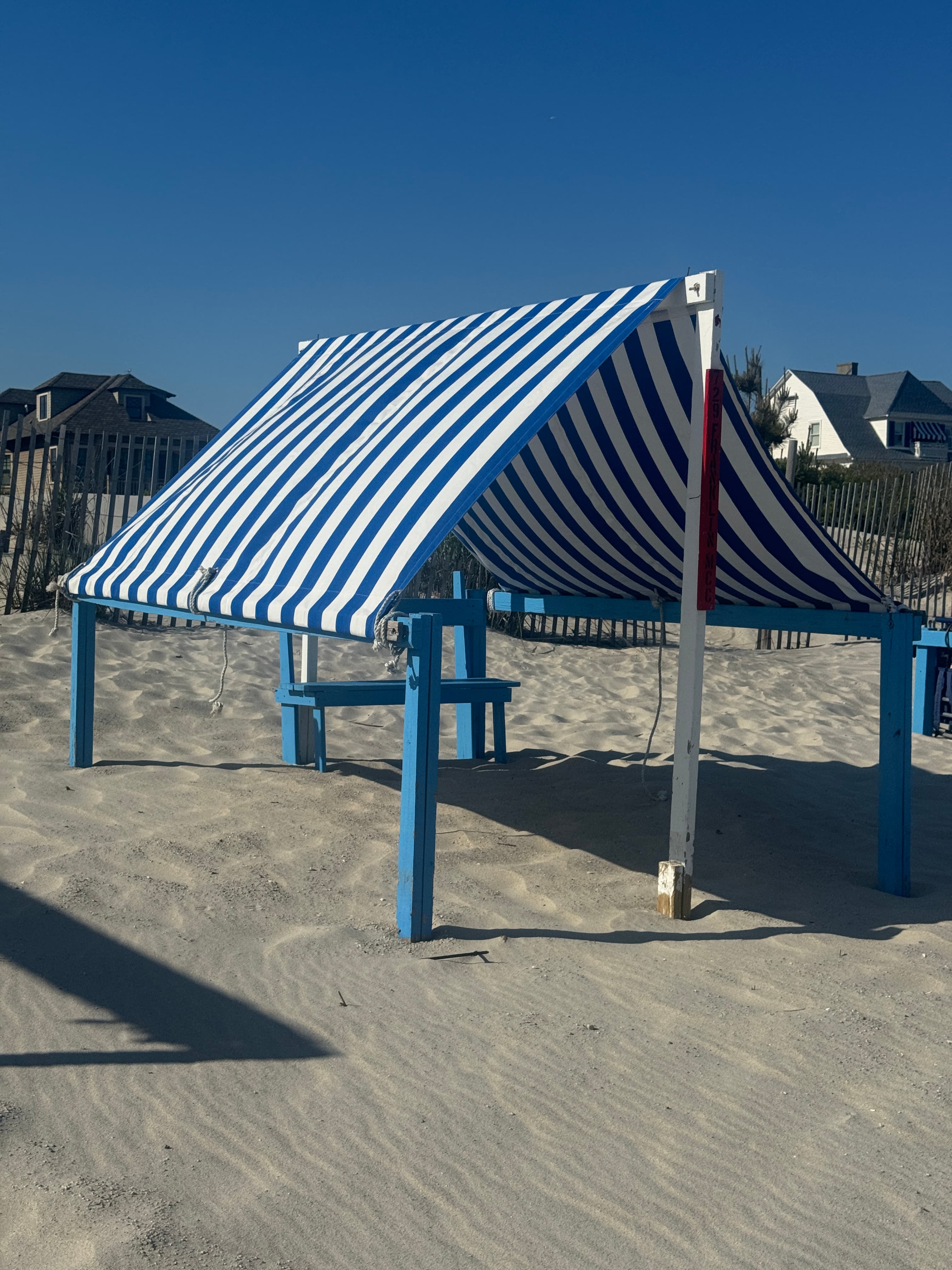 A blue-and-white striped beach cabana on the sand