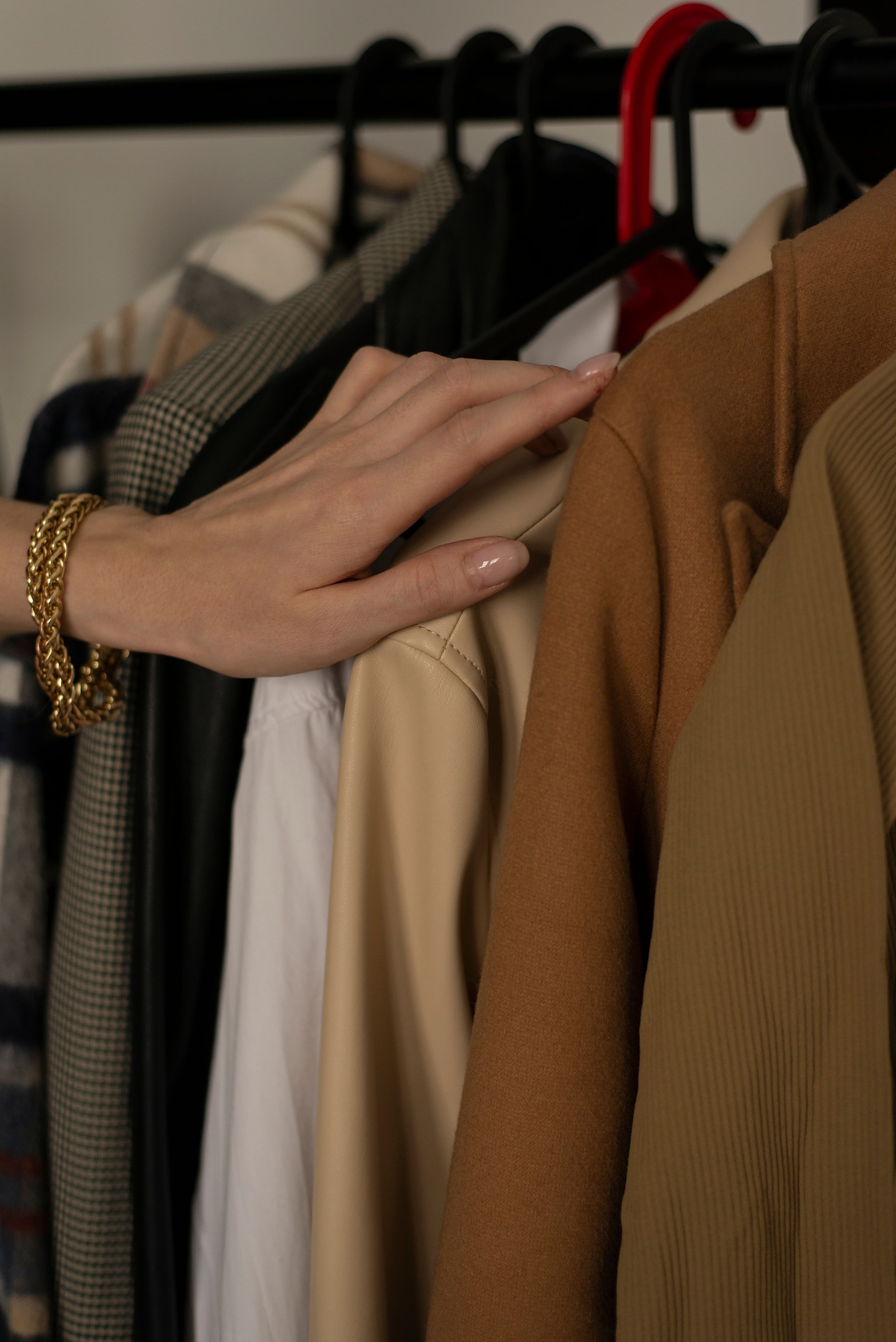 A hand resting on a coat along a wardrobe rail